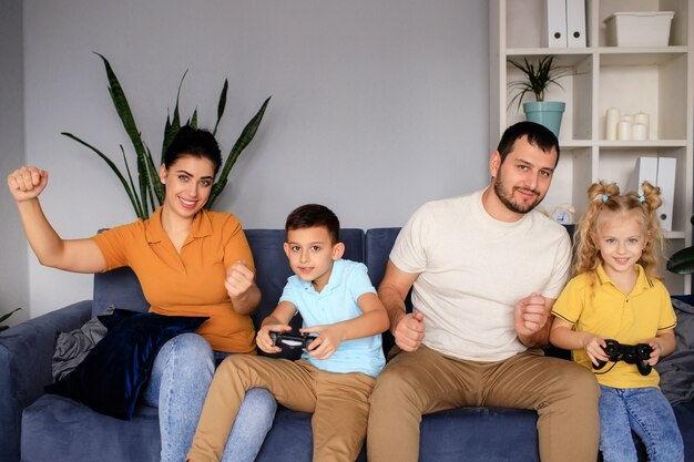 Hermosa madre y padre guapo con su hija e hijo pasando tiempo juntos en casa y jugando videojuegos. Concepto de familia feliz.