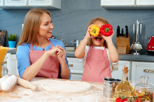 Hermosa madre y su adorable hija divirtiéndose en la cocina