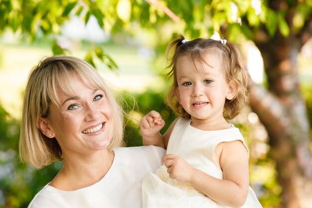 Hermosa madre con su hija en ropa ligera al aire libre en verano en el parque