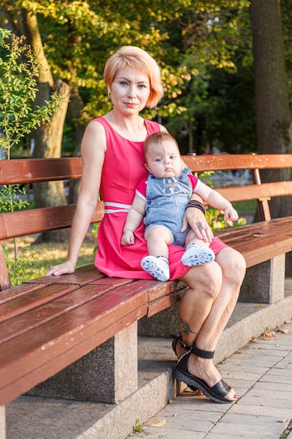 Hermosa madre con su hija y su hijo están sentados en un banco en el parque en verano