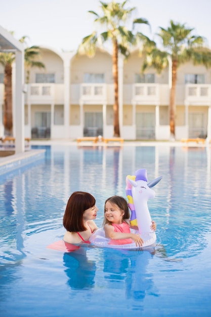 Hermosa madre con su linda hija con un anillo inflable en forma de unicornio