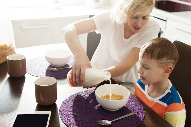 Hermosa madre y su lindo hijo comiendo cereales saludables para el desayuno