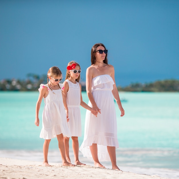 Hermosa madre y sus adorables hijas en la playa