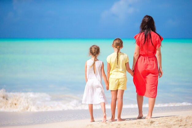 Hermosa madre y sus adorables hijas en la playa