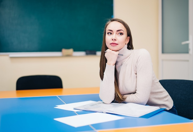 Hermosa maestra de escuela sentada en el aula