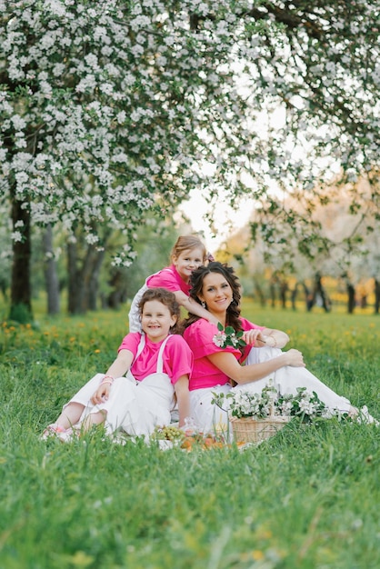 Hermosa mamá y dos hijas con ropa brillante se divierten en primavera en el parque