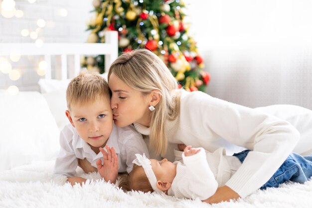 Hermosa mamá con dos hijos celebran Navidad Año Nuevo en casa con árbol de Navidad