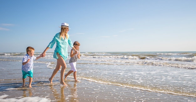 Hermosa mamá juega con sus hijos en el mar