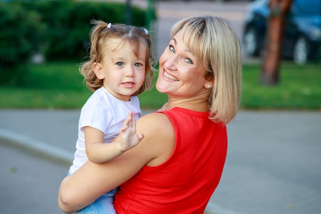 Hermosa mamá rubia con una camiseta roja con su hija. retrato de grupo