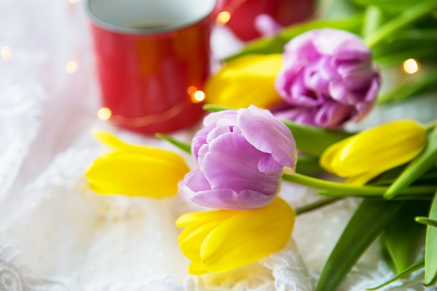 Hermosa mañana, dos tazas de café y un ramo de tulipanes brillantes y hermosos. Primer plano de flores.