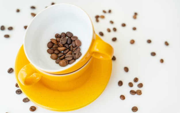 Hermosa mañana el proceso de hacer café una taza amarilla sobre una mesa blanca esparcida granos de café