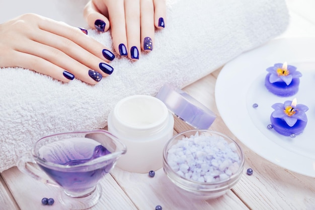 Hermosa manicura azul con elementos esenciales de spa sobre fondo de madera