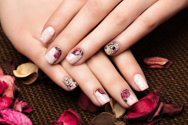 Hermosa manicura con flores en los dedos femeninos Diseño de uñas Foto de primer plano tomada en el estudio sobre un fondo blanco