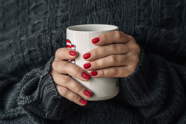 Hermosa manicura roja con una taza de té.