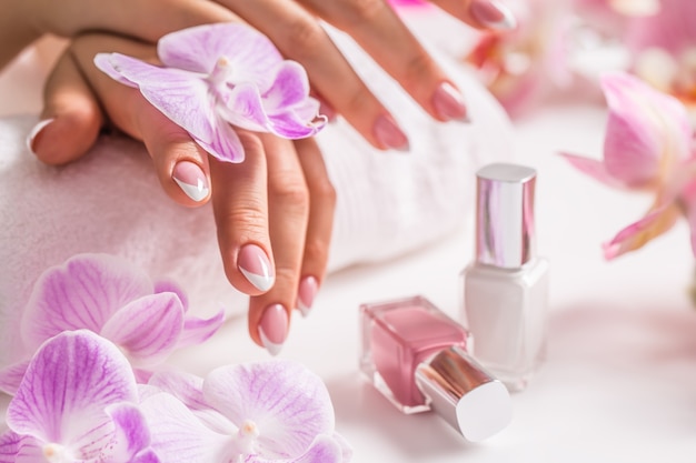 Hermosa manicura de uñas con decoración de orquídea rosa.