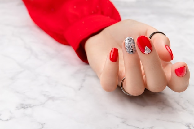 Foto hermosa mano femenina bien cuidada con diseño de uñas navideñas