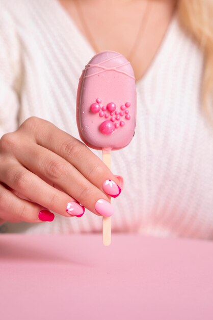 Hermosa mano femenina con diseño de flores de uñas de manicura rosa con helado