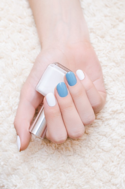 Hermosa mano femenina con diseño de uñas azul y blanco