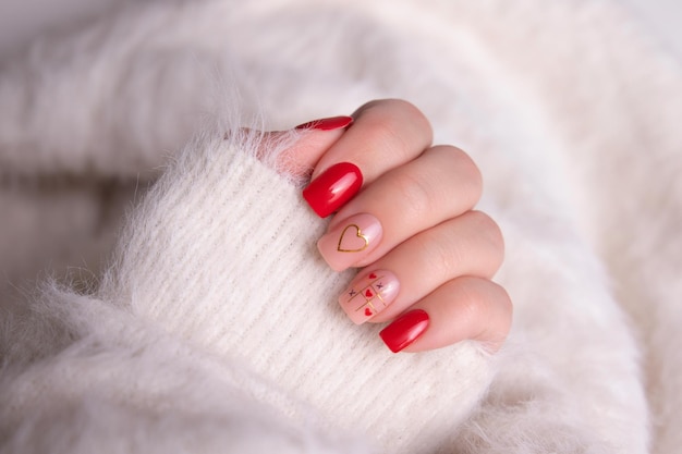 Foto hermosa mano femenina con uñas de manicura roja corazón y diseño de día de san valentín