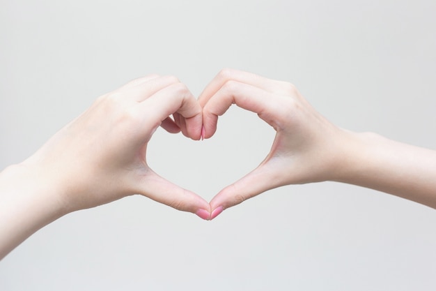 Hermosa mano femenina muestra el símbolo del corazón como signo de amor en concepto de manicura.