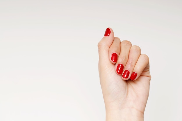 Foto hermosa mano femenina pintando gel acrílico uñas rojas estilo de moda