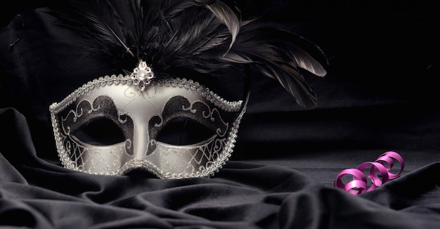 Hermosa máscara de carnaval veneciano sobre tela oscura con vela y cinta