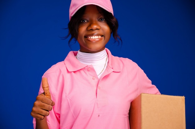 Hermosa mensajera negra sosteniendo una caja hace un gesto de aprobación