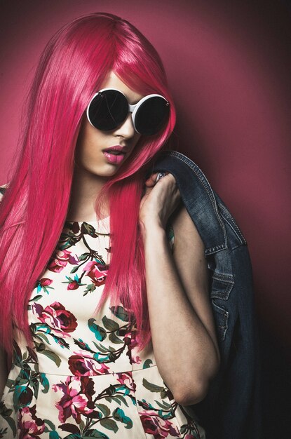 Hermosa modelo con cabello rosado y maquillaje con grandes gafas de sol