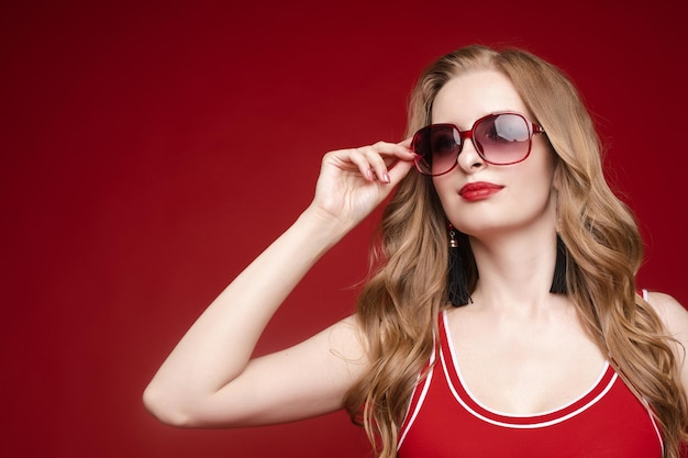 Hermosa modelo femenina posando sobre fondo rojo.