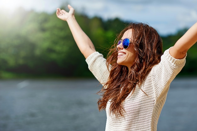 Foto hermosa modelo femenino sonriente disfrutando de libertad con manos levantadas