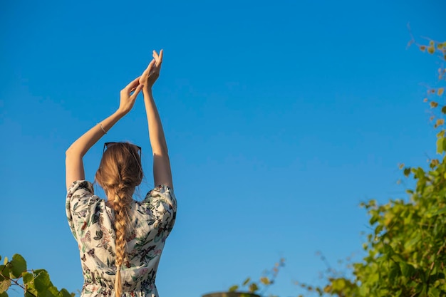 Foto una hermosa modelo de moda disfruta de la naturaleza, respira aire fresco en un jardín de verano contra la espalda