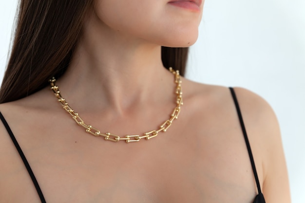 Hermosa modelo morena en cadena de collar de metal dorado moderno