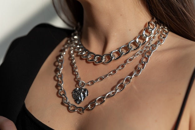 Hermosa modelo morena en moderno collar de metal plateado con muchas cadenas