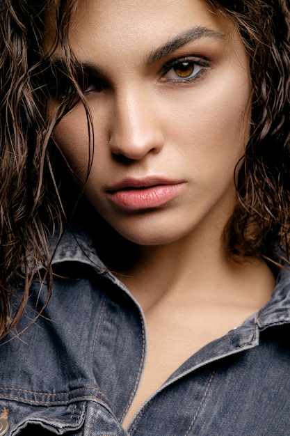 hermosa modelo con piel limpia y cabello rizado en jeans chaqueta vaquera