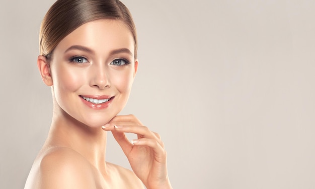 Hermosa modelo con piel limpia y fresca está tocando su propia cara Sonrisa en la cara perfecta Cosmetología