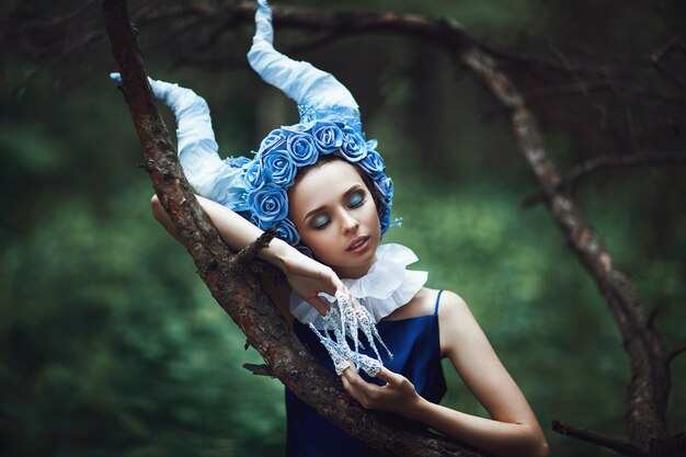 Hermosa modelo posa en un bosque con cuernos azules