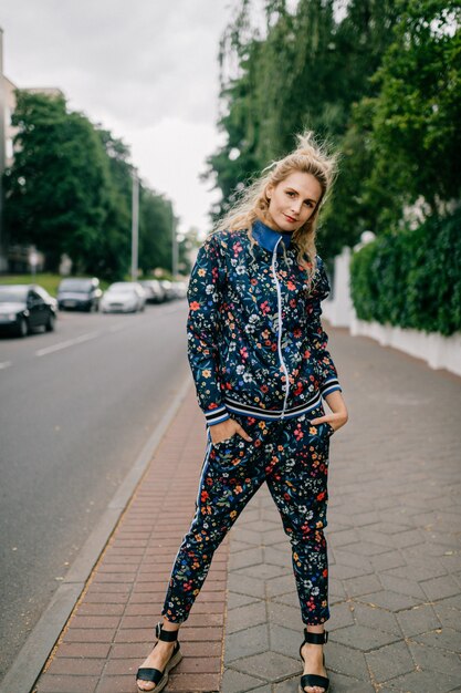 Hermosa modelo rubia con estilo en traje de color posando en la calle