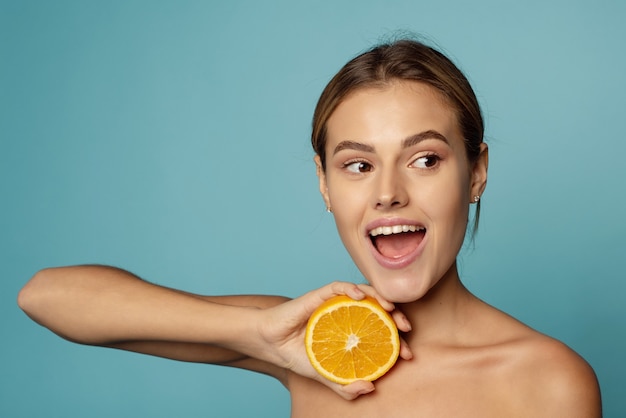 Hermosa modelo sonriente con maquillaje natural y cítricos