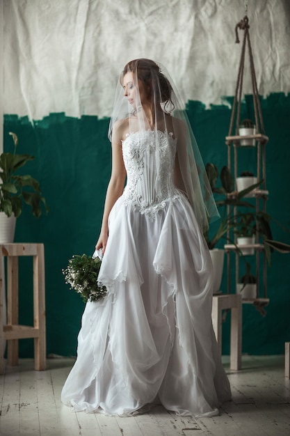 Hermosa modelo con vestido de encaje blanco está posando en un estudio interior