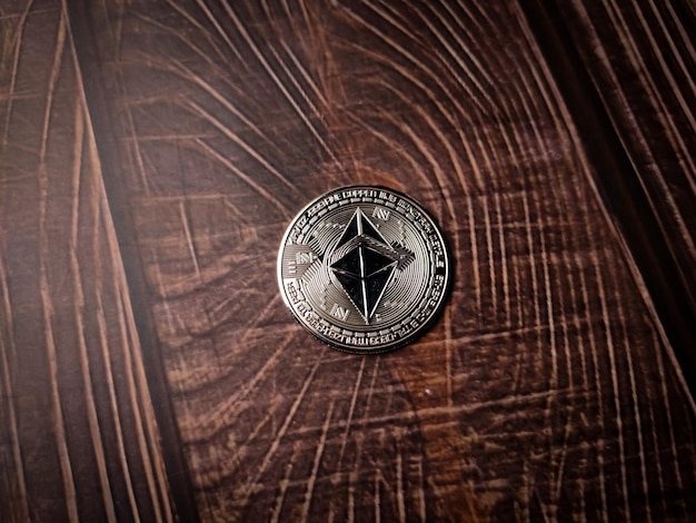 Una hermosa moneda criptográfica digital etérea plateada sobre una mesa de madera