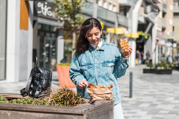 Hermosa morena 20-30 disfrutando de la deliciosa comida del restaurante de comida para llevar en la calle a la hora del almuerzo