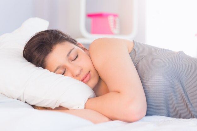 Hermosa morena acostada en la cama durmiendo