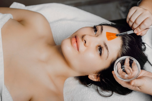 Foto hermosa morena apoyada en una cama de spa con los ojos abiertos con máscara anti-edad en una máscara de resort wellens.