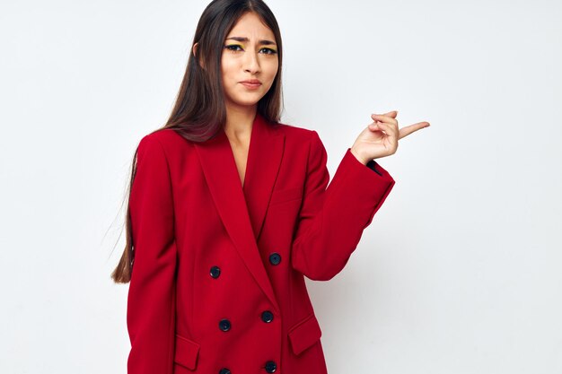 Hermosa morena en una chaqueta roja cosméticos sonrisa fondo claro inalterado