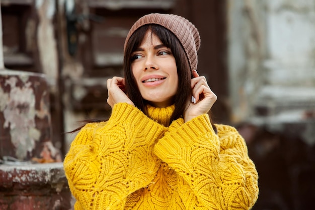 Hermosa morena europea vestida con un suéter de lana amarillo y un sombrero afuera