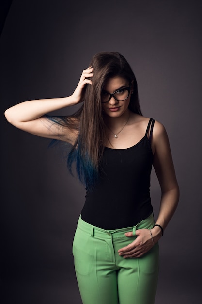 Hermosa morena joven en gafas y pantalones verdes