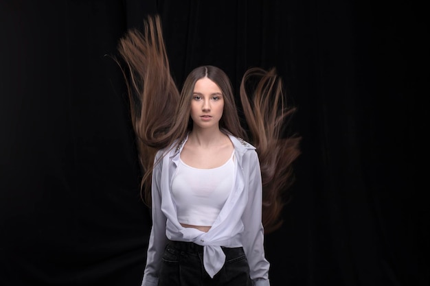 Hermosa morena con el pelo largo y volador sobre un fondo oscuro.