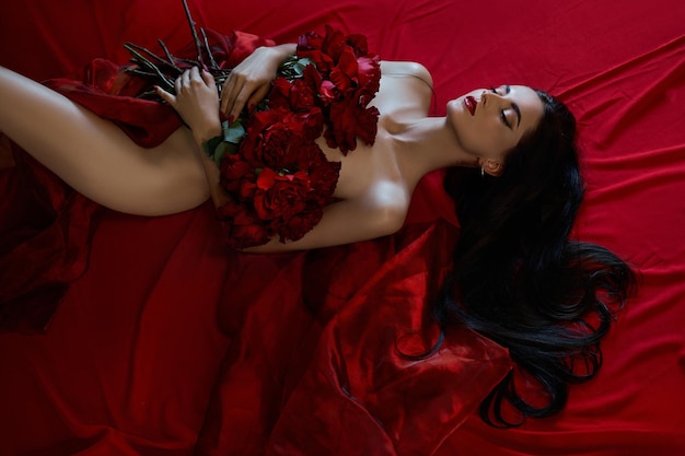 Hermosa morena sexy con un ramo de rosas rojas en el suelo, partes del cuerpo desnudo, retrato erótico de una mujer