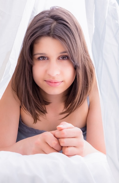 Foto hermosa morena sonriendo a la cámara en la cama