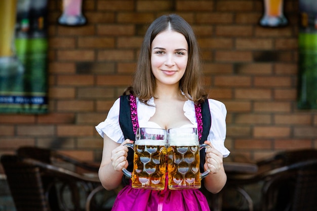 Foto la hermosa morena sostiene 2 pintas de cerveza en el oktoberfest en alemania